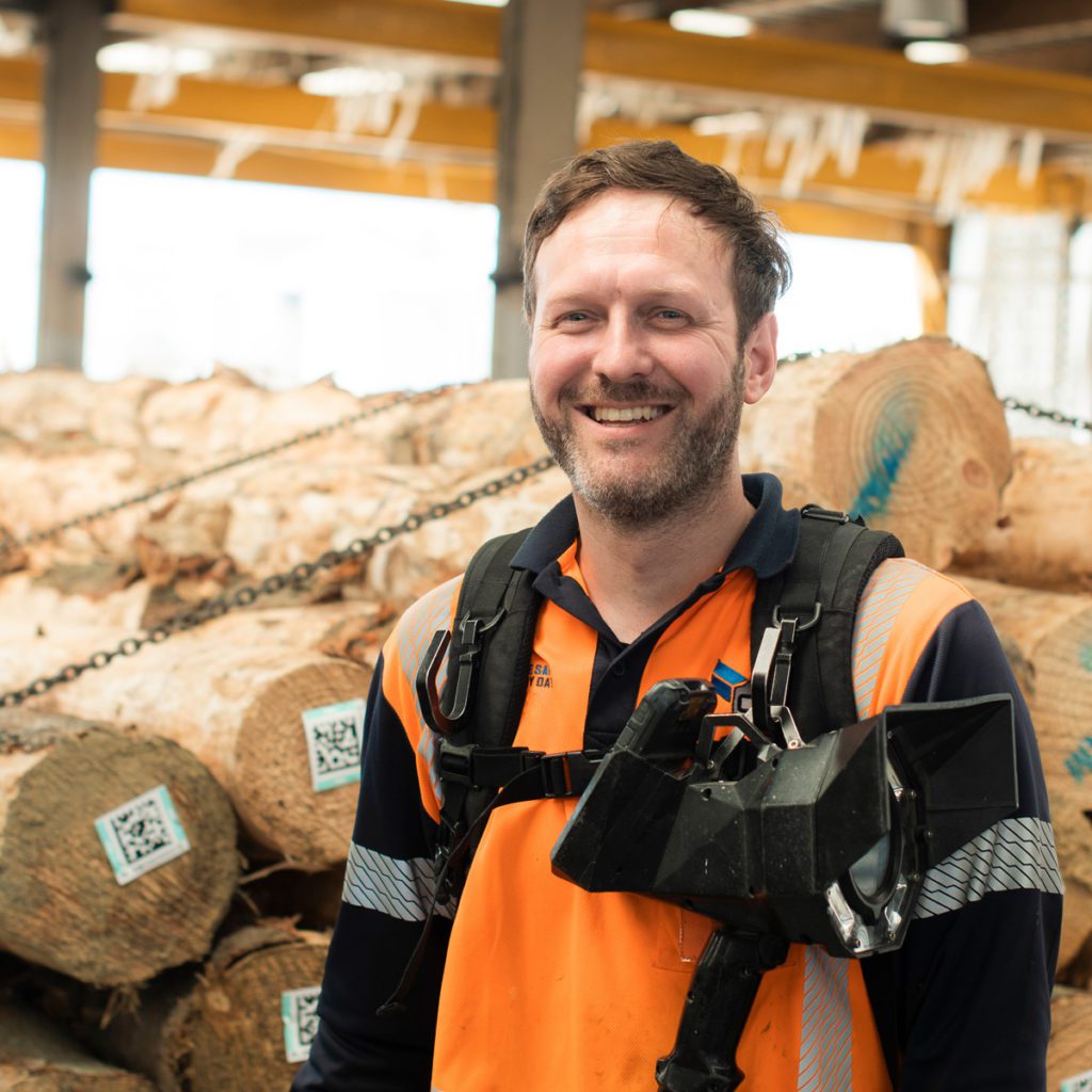 Male wharf hand with log pile in Tauranga